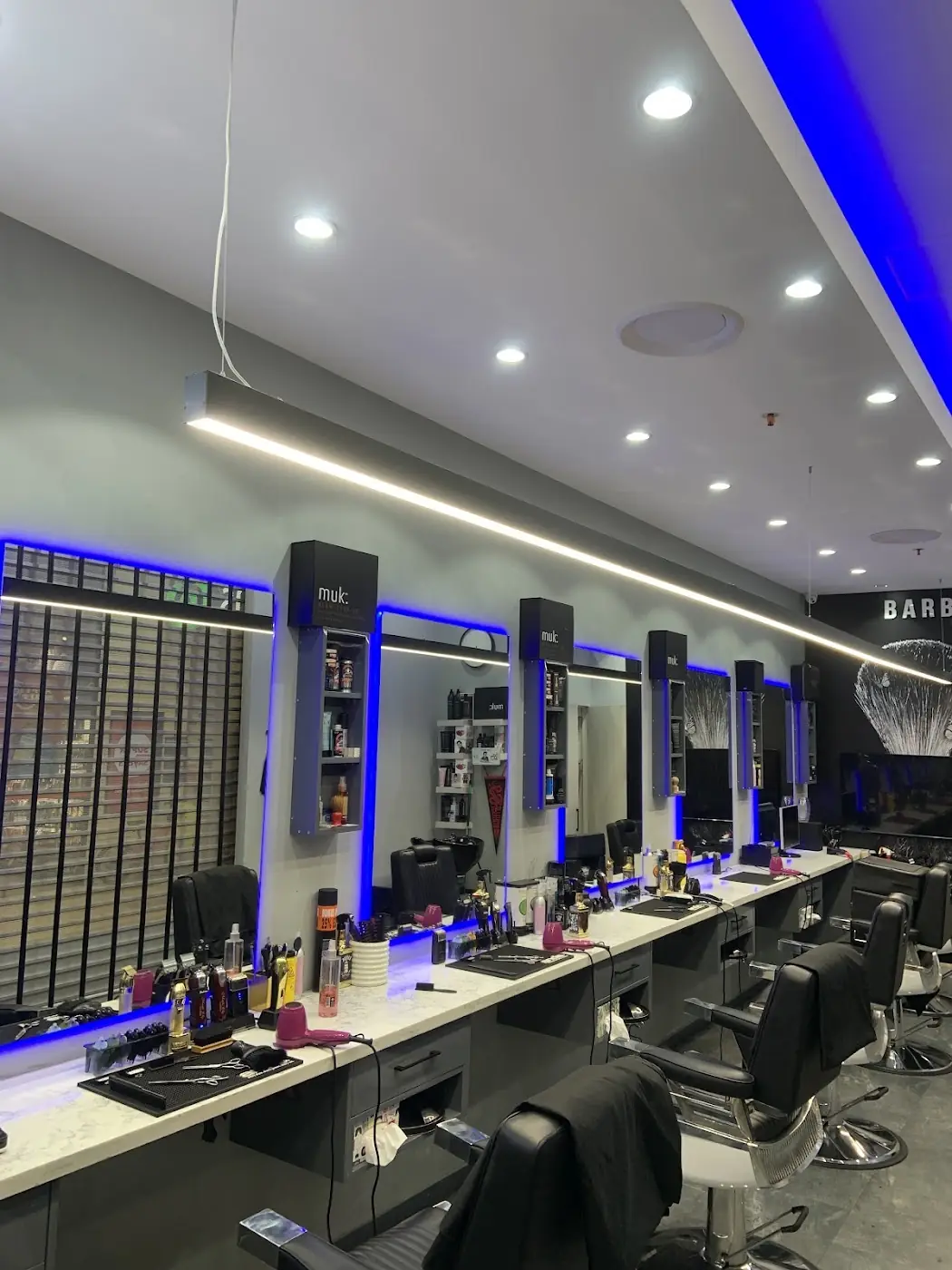 The row of barber chairs inside BARBERIO, lit in blue